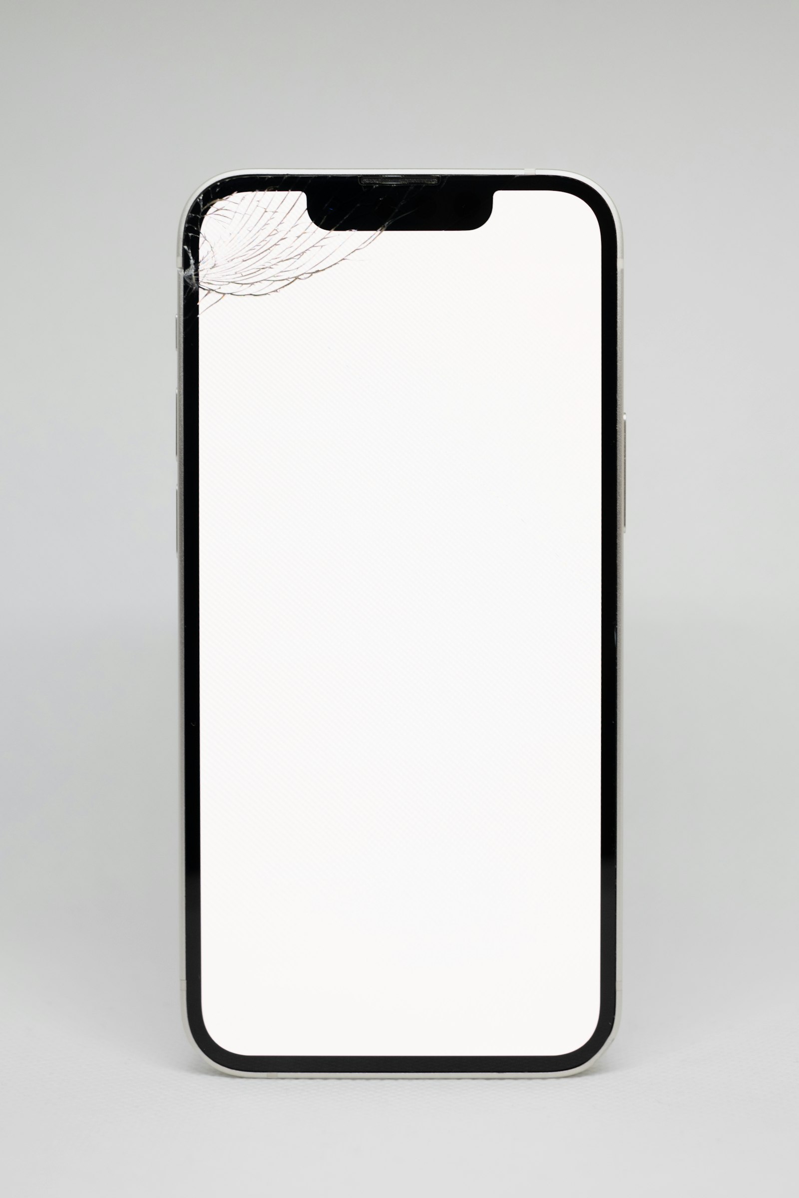 A phone with a cracked screen corner on a plain grey background