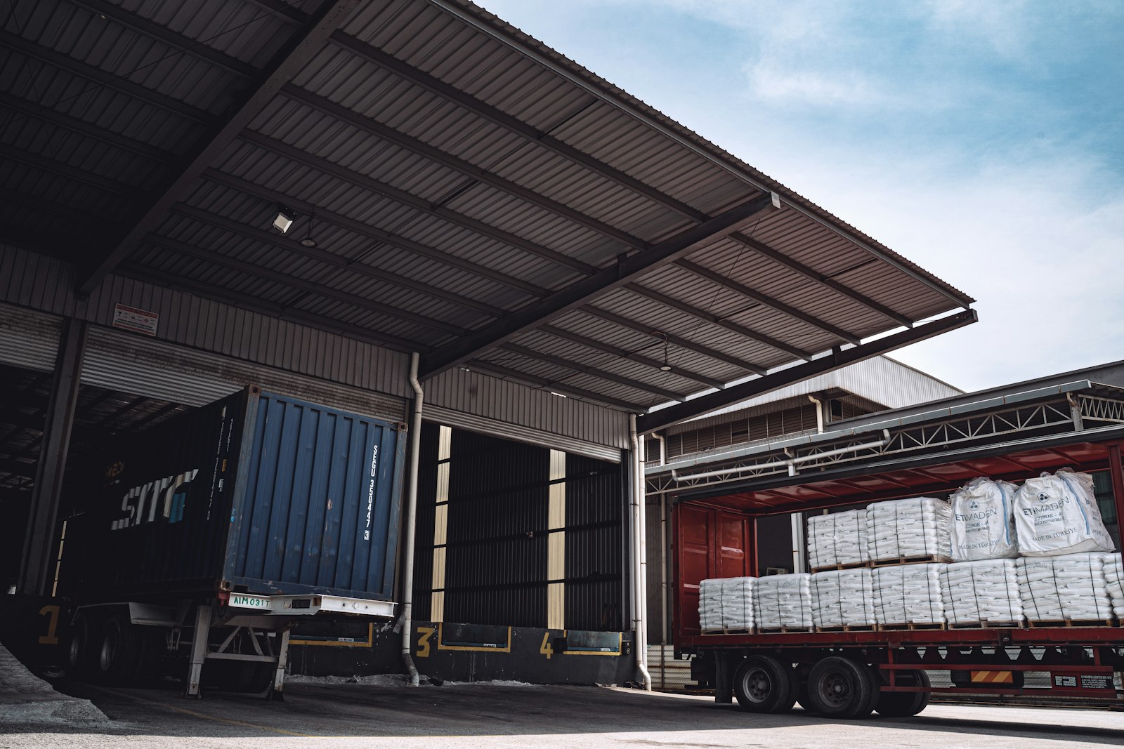 A covered loading dock with a blue container trailer backed into the bay