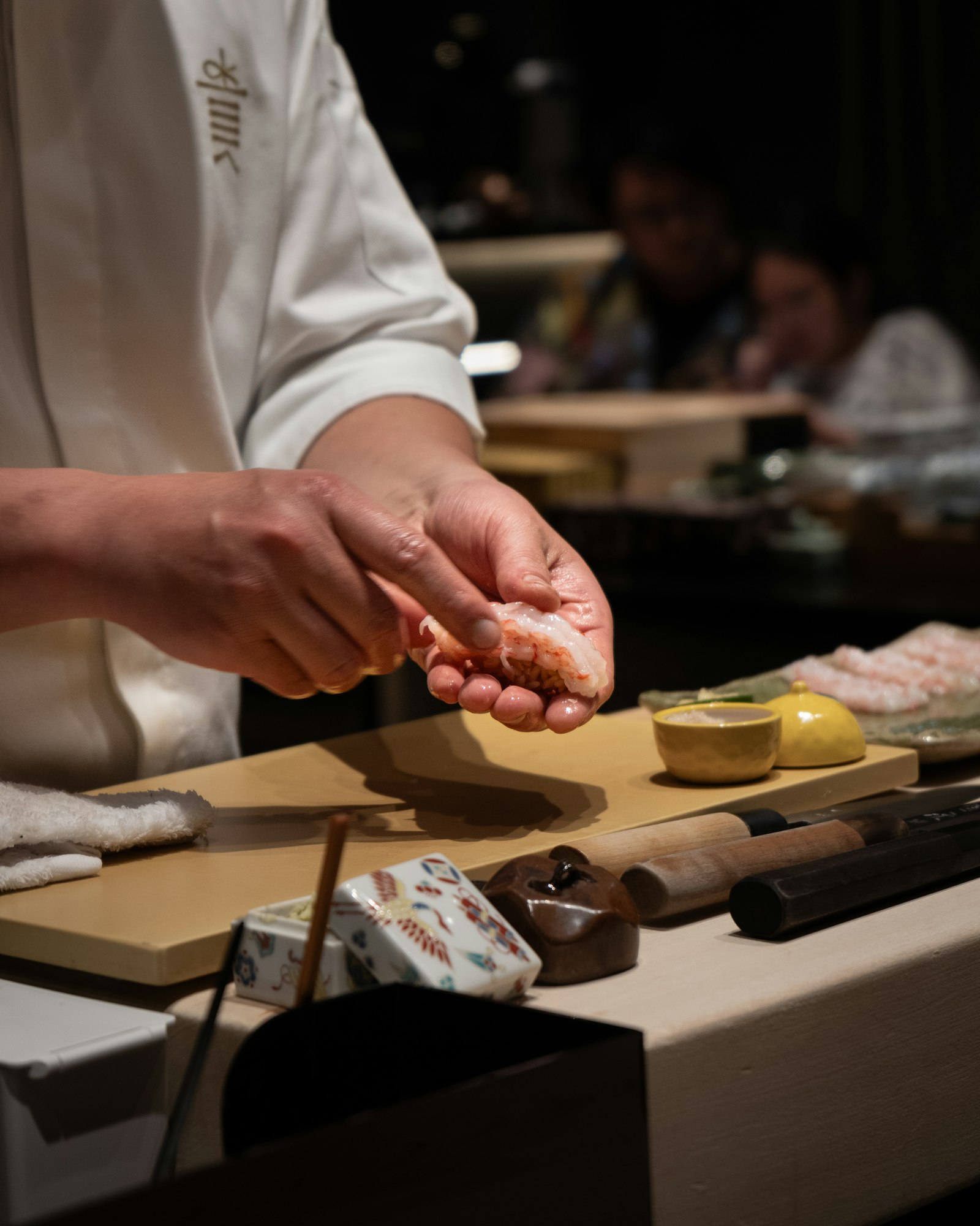 A chef’s hands forming nigiri at the counter