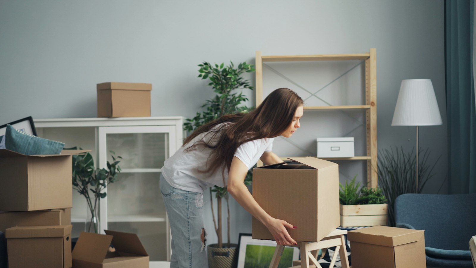 A woman unpacking moving boxes in a bright living room