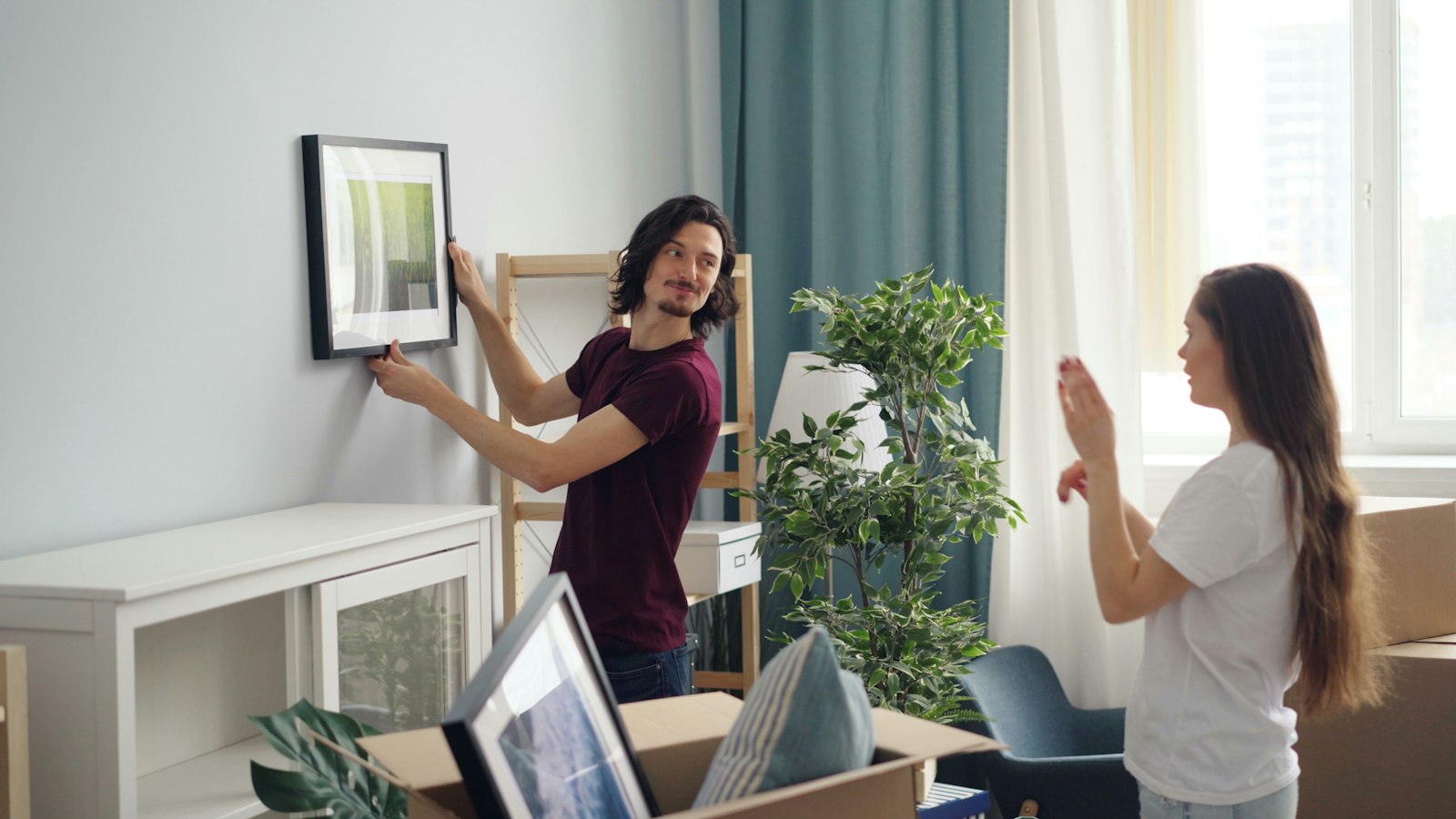 A couple hanging a picture among moving boxes in a new flat