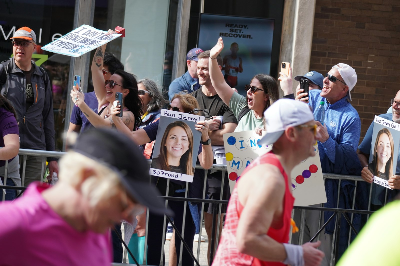 A crowd behind barriers cheering with handmade signs