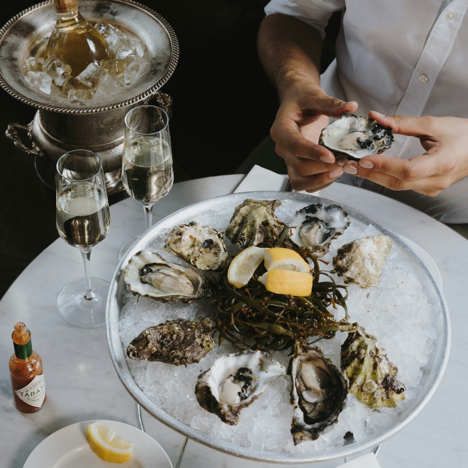 An oyster platter on ice with glasses of champagne