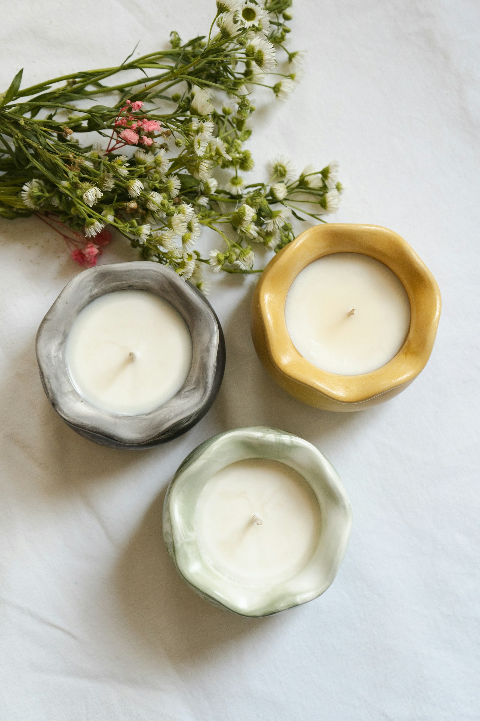 Candles in handmade glazed vessels with wildflowers