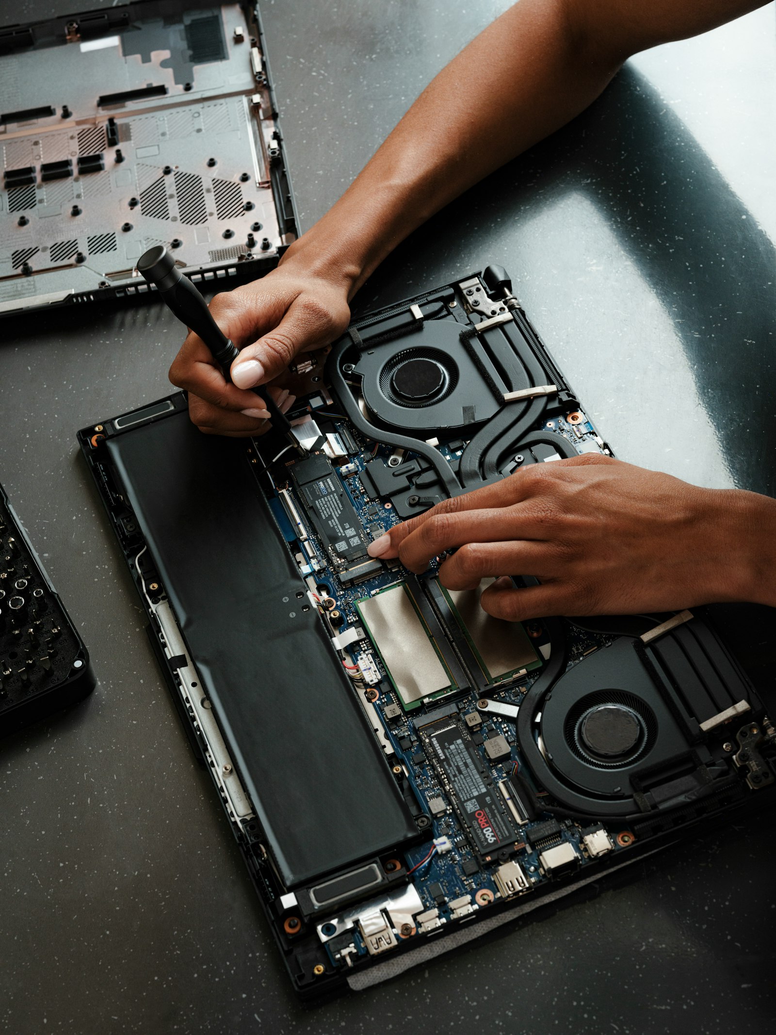 Hands with a precision screwdriver inside an open laptop