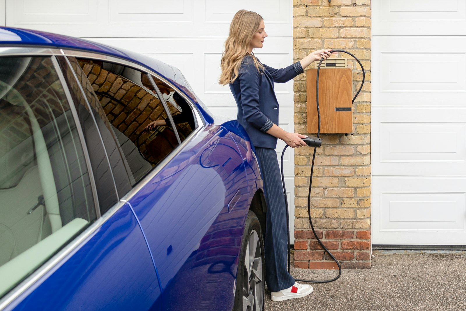A woman plugging an electric car into a home charger