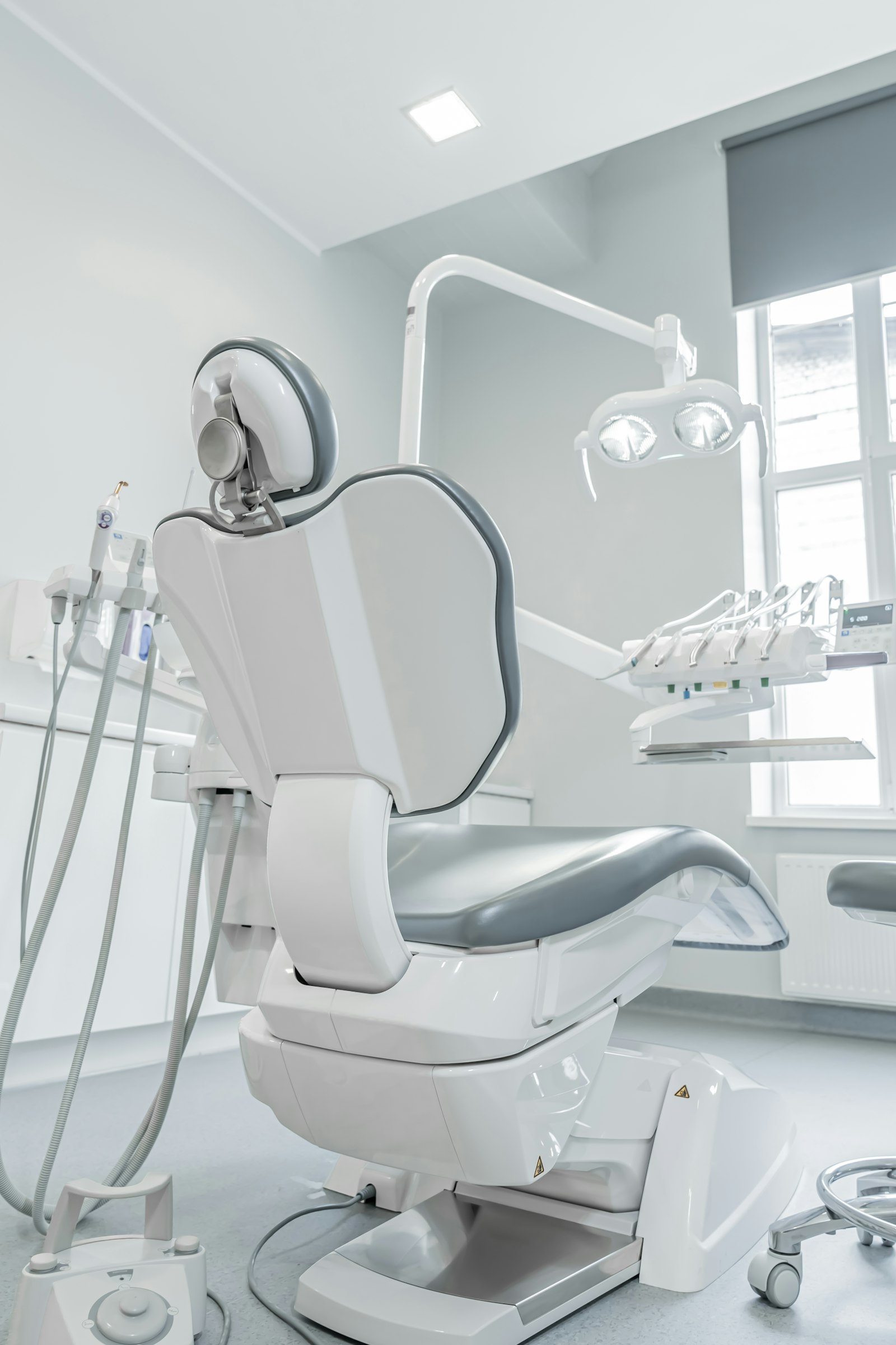 A white dental chair beside a window