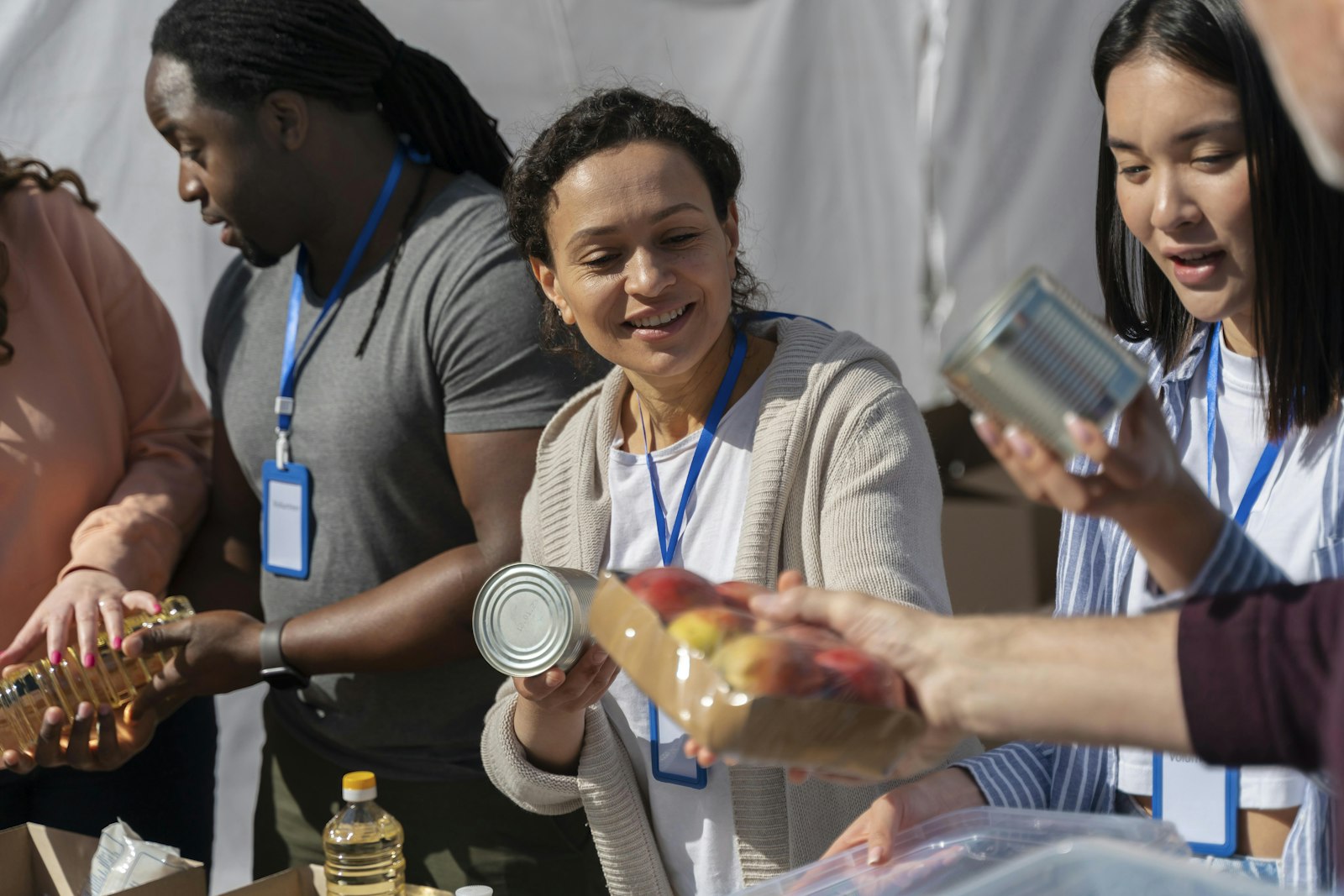 Volunteers passing tins across a distribution table