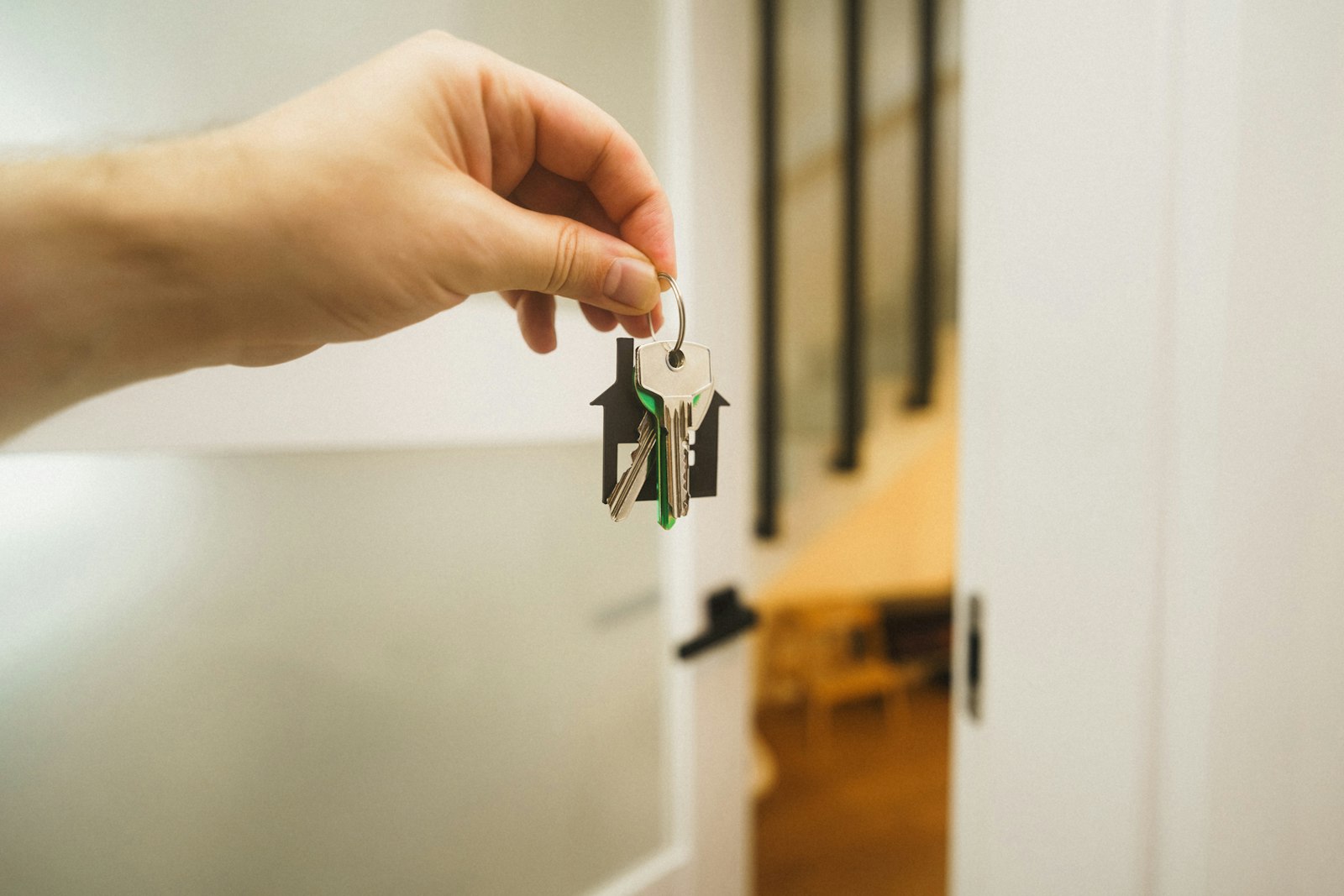 A hand holding a key on a house keyring at an open front door