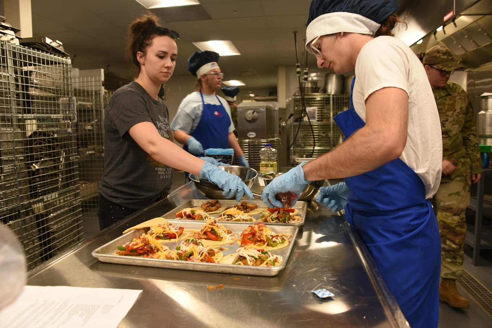 Volunteers in aprons plating meals in a community kitchen