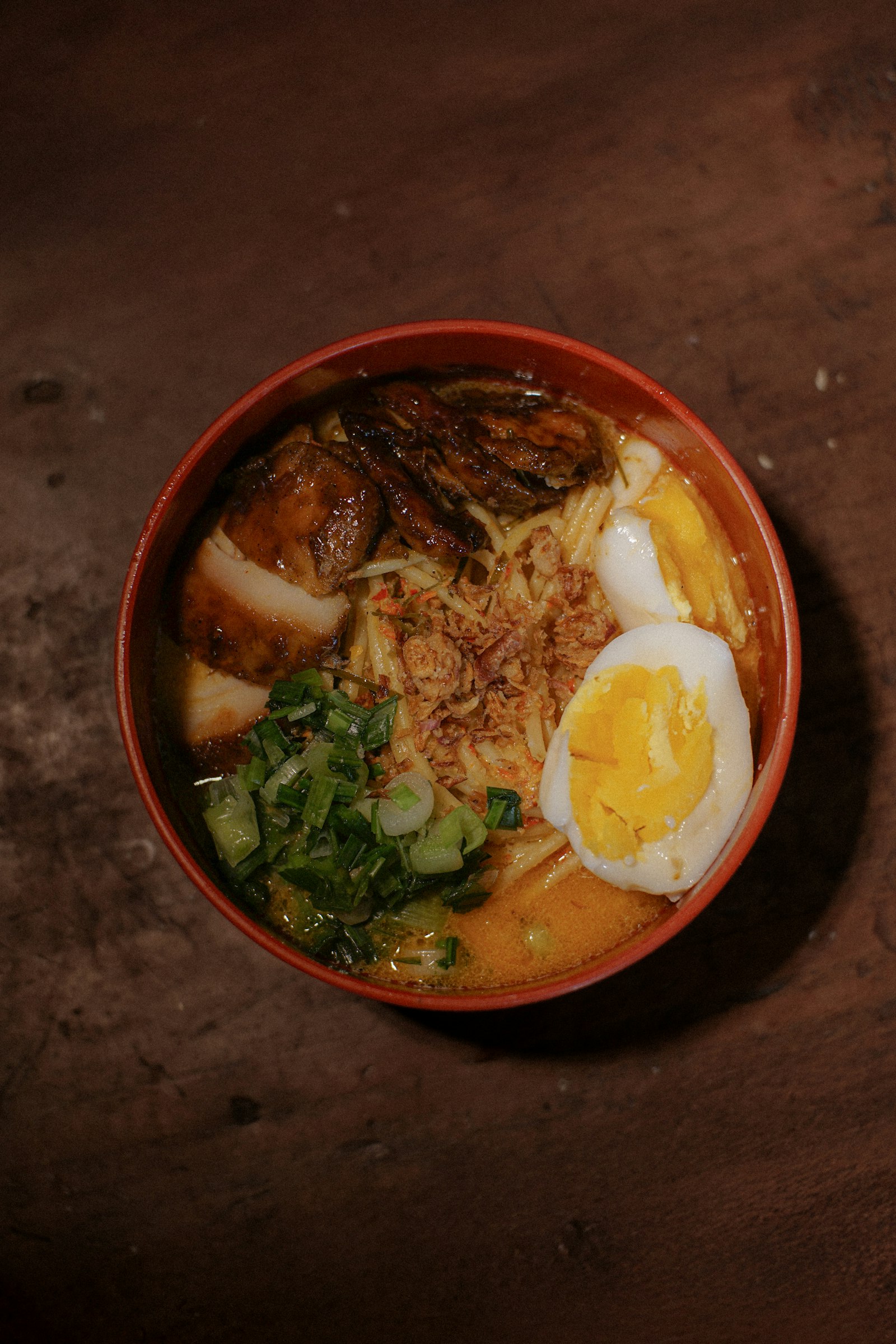 A bowl of ramen with braised pork, a halved egg and spring onion