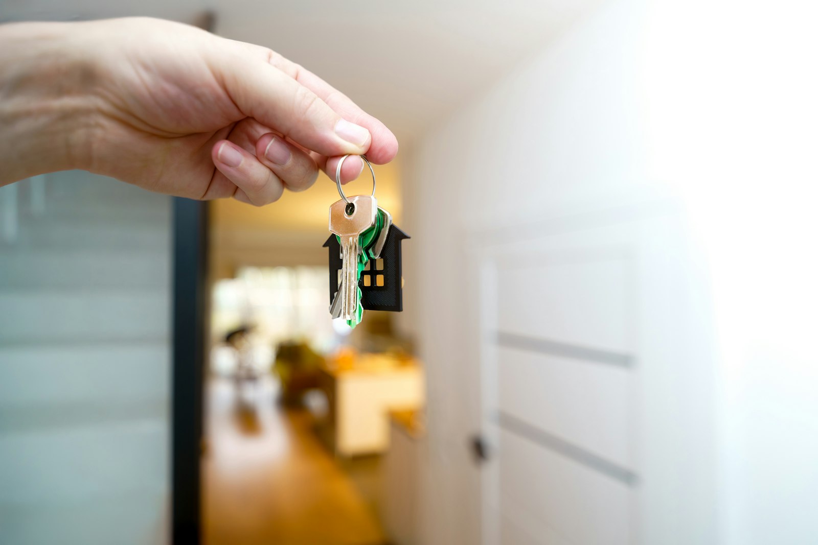 A hand holding house keys up in a bright hallway