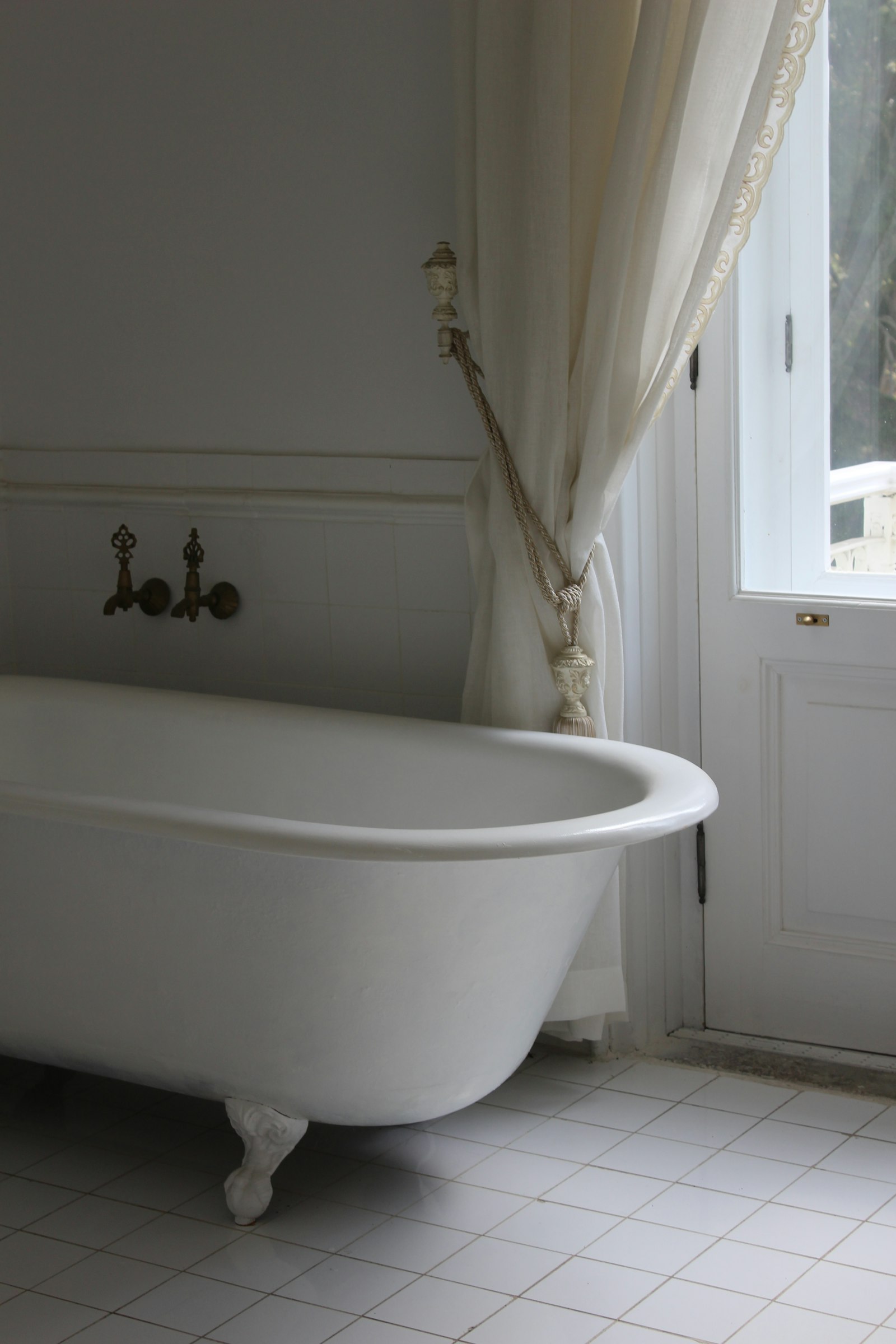 A claw-foot roll-top bath by a window