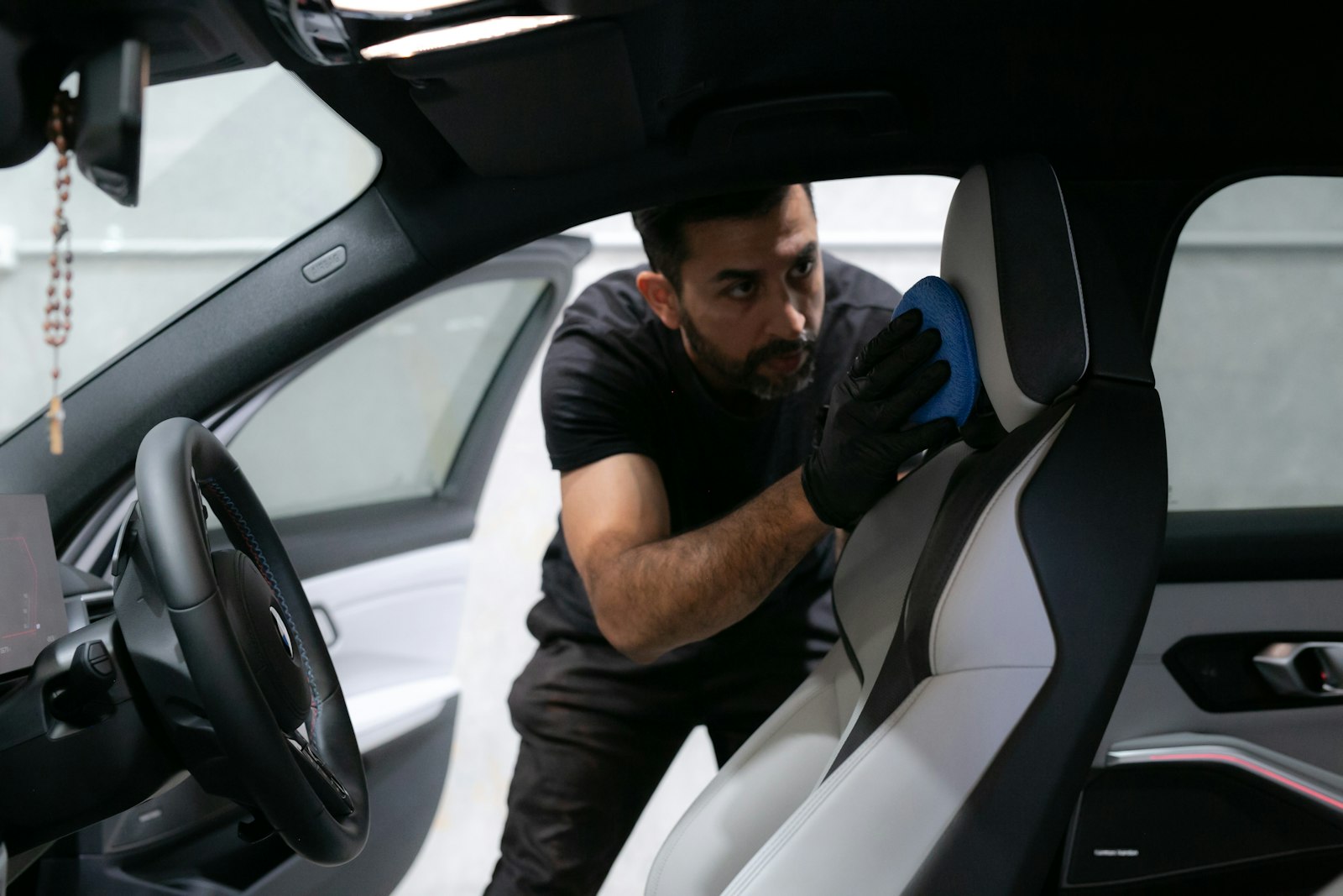 A man in gloves cleaning the seat of a car between hires