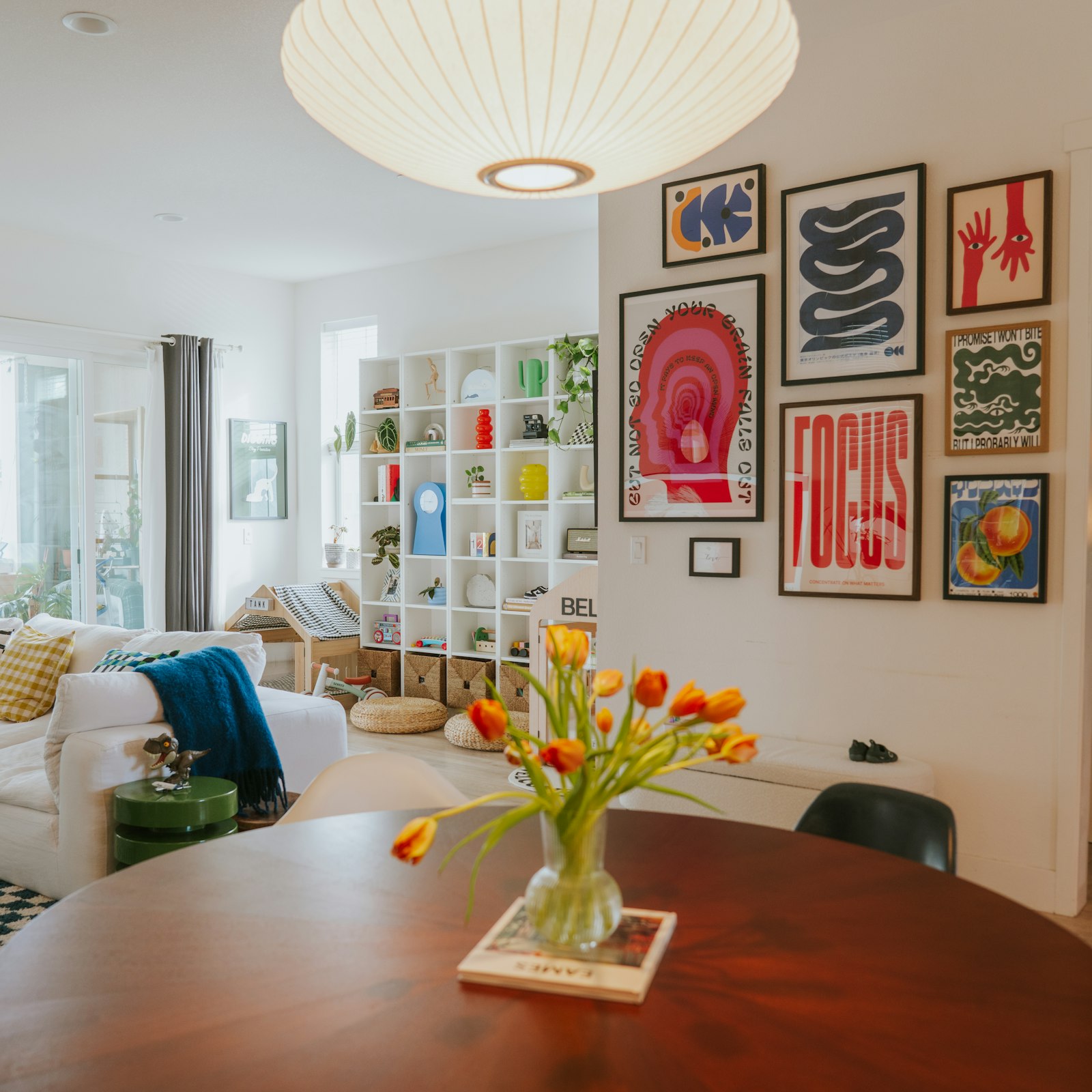 A bright living and dining room with tulips and framed prints