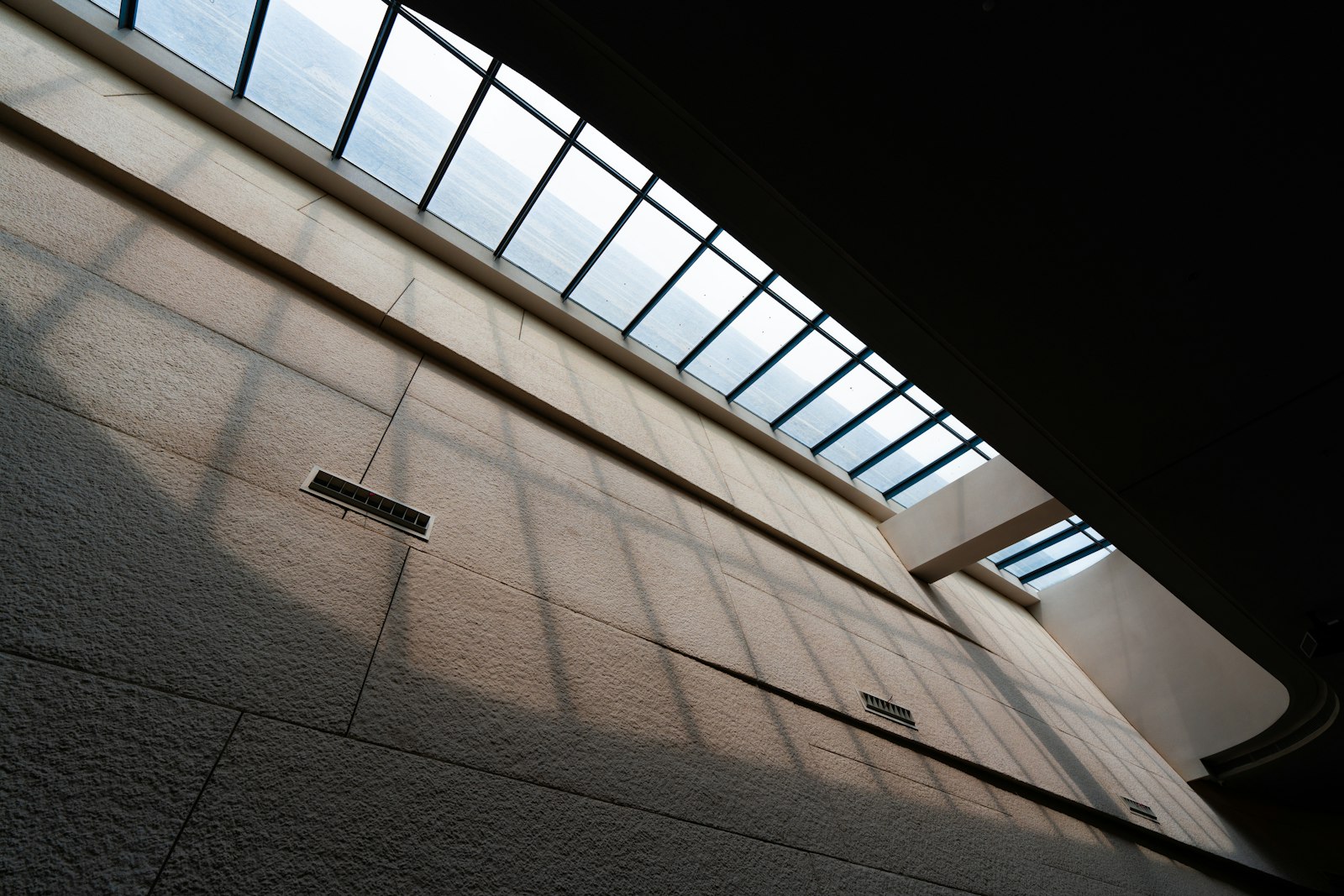A top-lit concrete interior with light on a textured wall