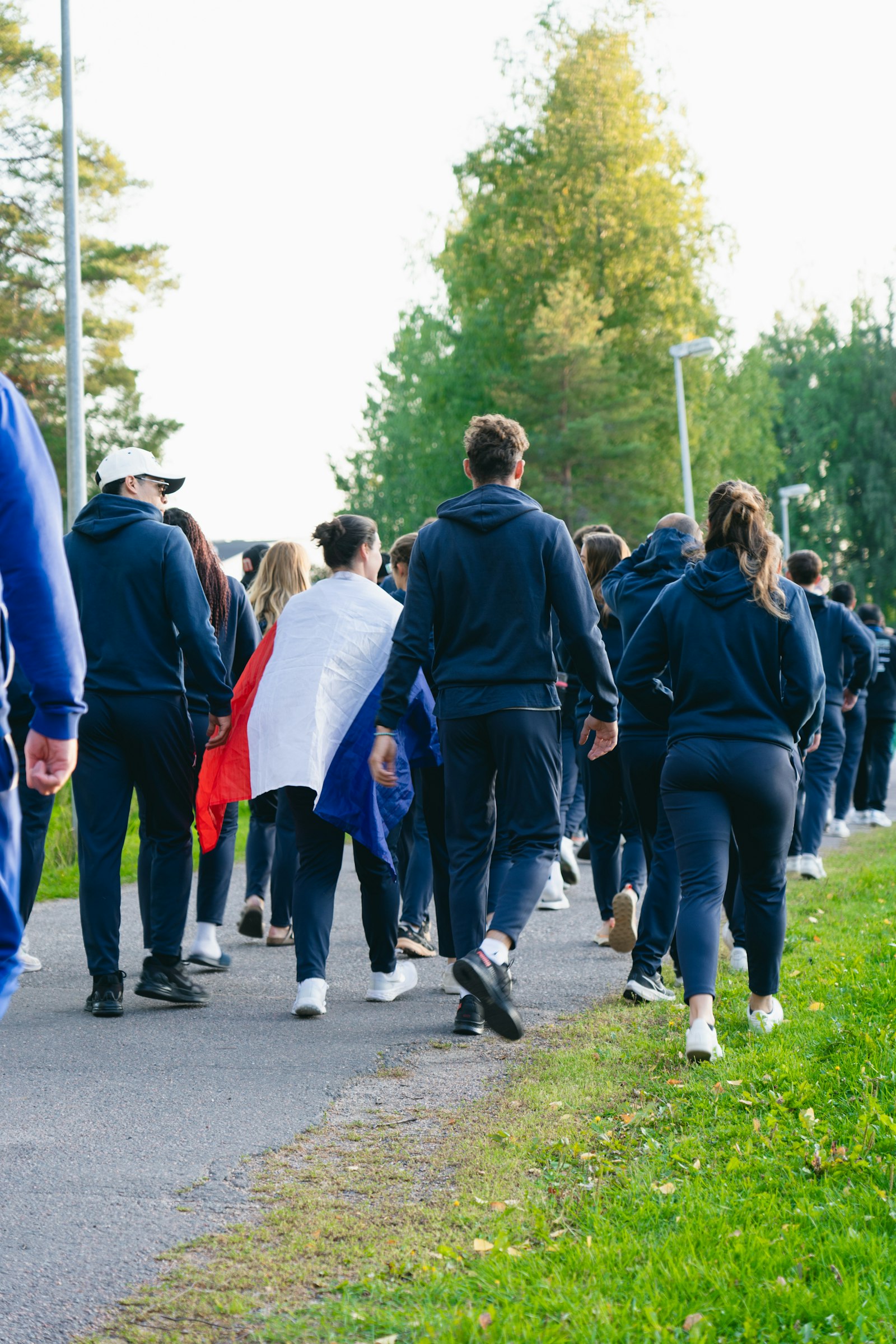 A group walking a path in matching hoodies, one carrying a flag