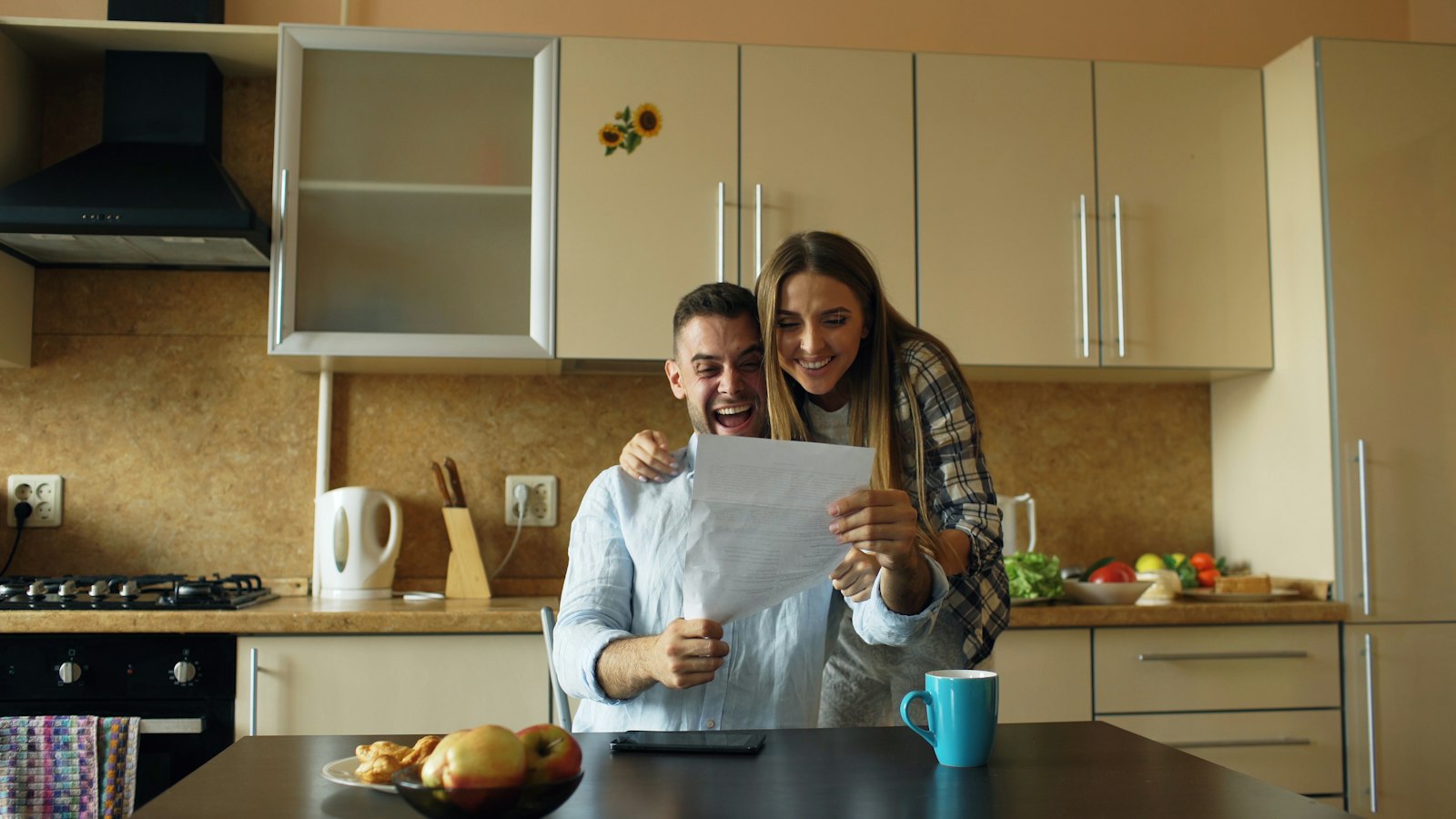 A couple reading a letter together in their kitchen