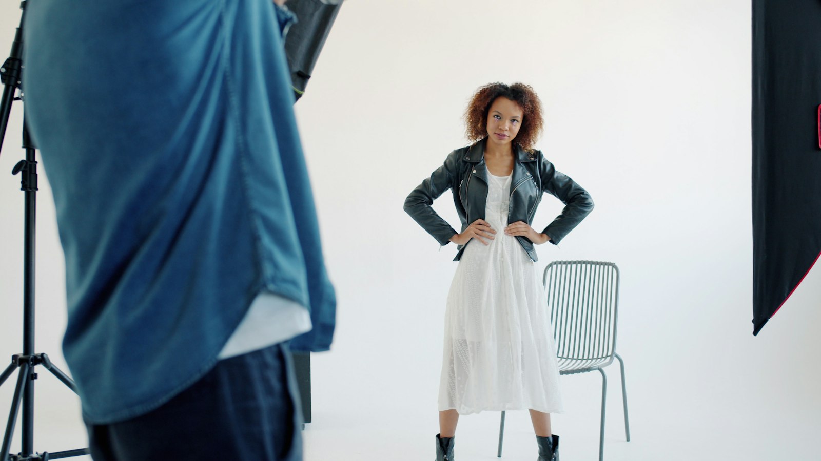 A model in a white dress and leather jacket in the studio