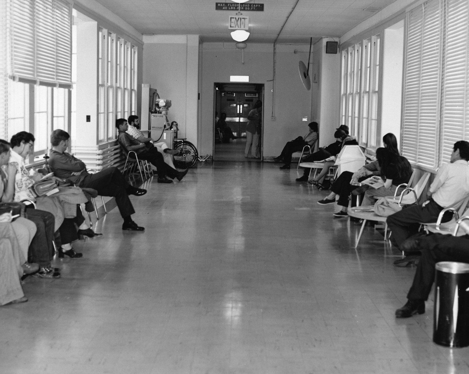 People waiting on chairs in a bright hallway