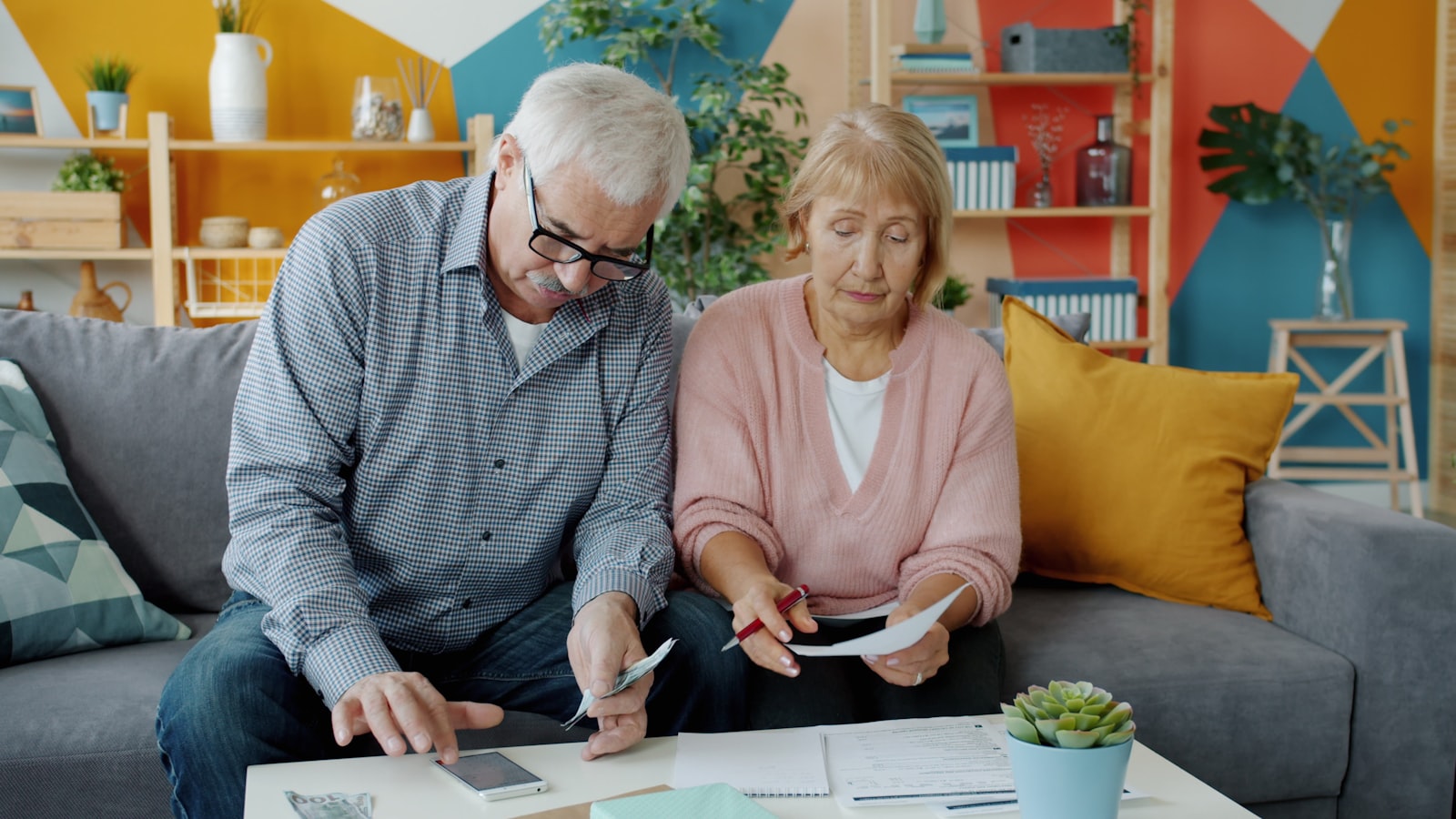 An older couple going through documents together on a sofa at home