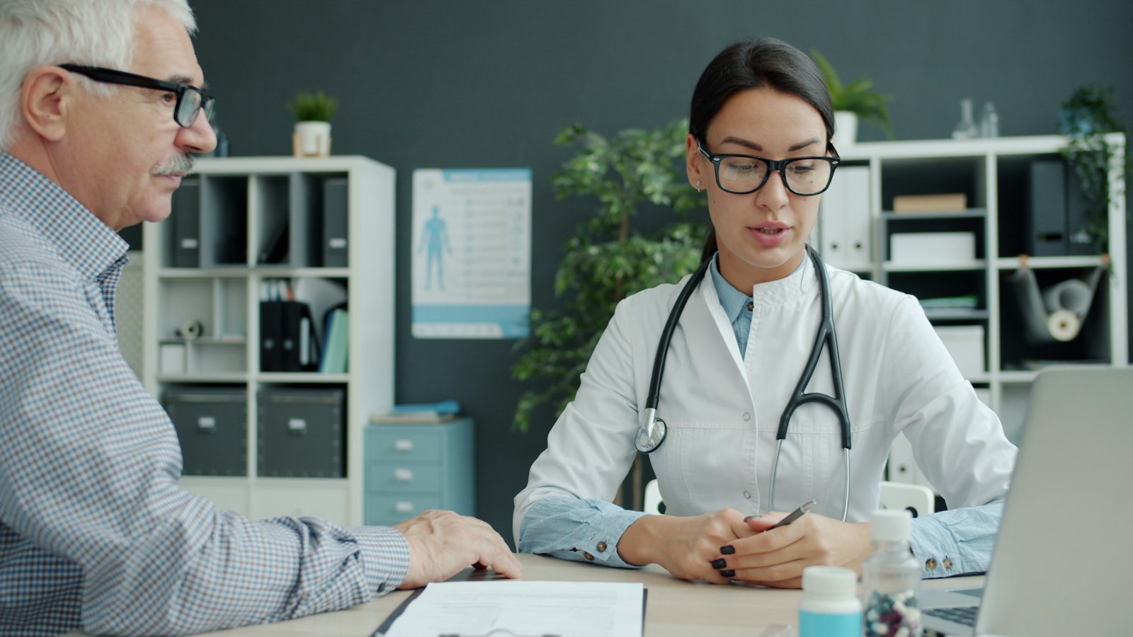A doctor talking with an older patient across a desk