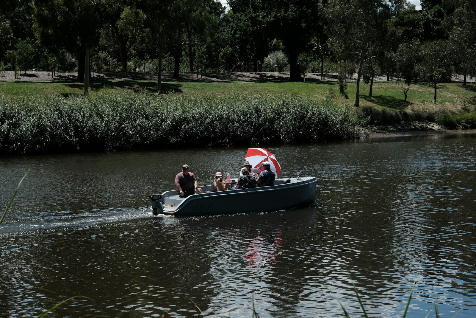 A family on a small open motorboat on a reedy river