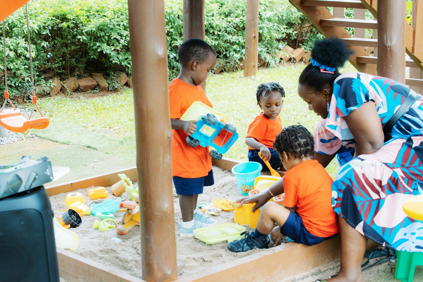 Children playing in a sandbox with an adult
