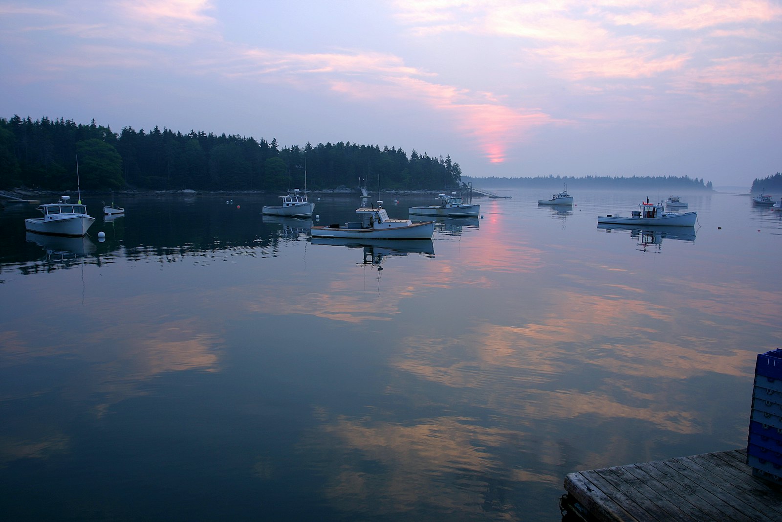 Fishing boats at anchor at sunrise, the water pink