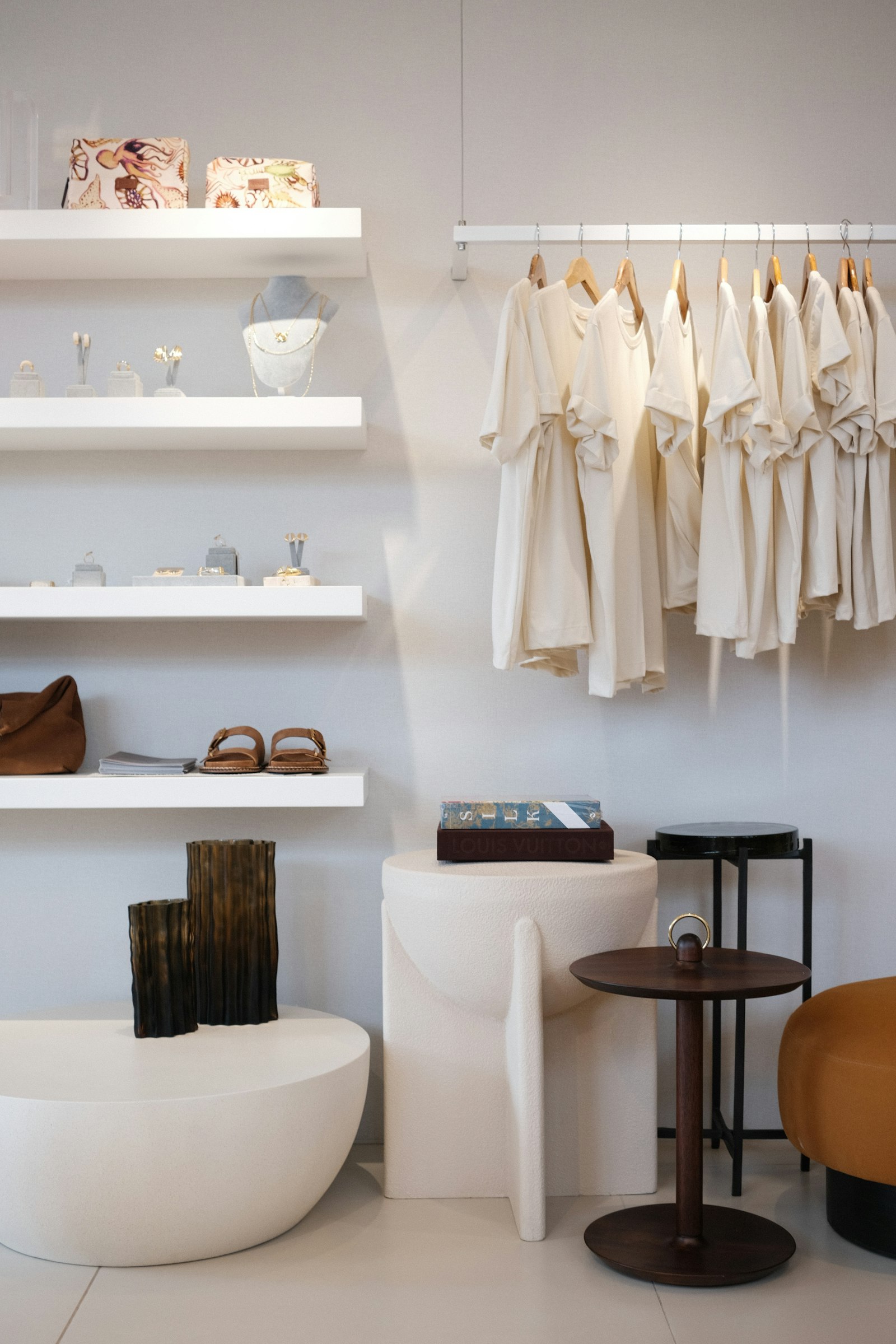 White shelves of bags and sandals beside a rail of shirts