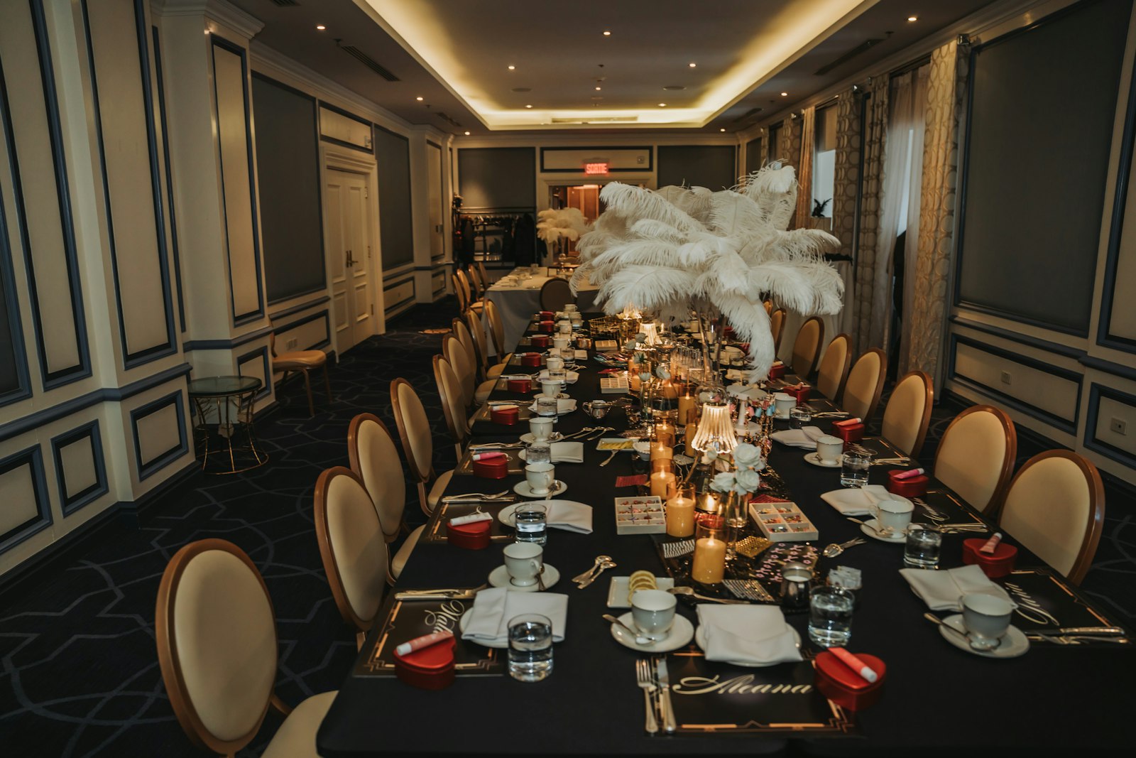A black banquet table with white feather centrepieces