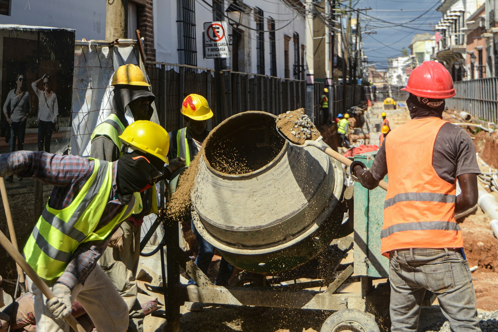 Workers in hard hats loading a small cement mixer