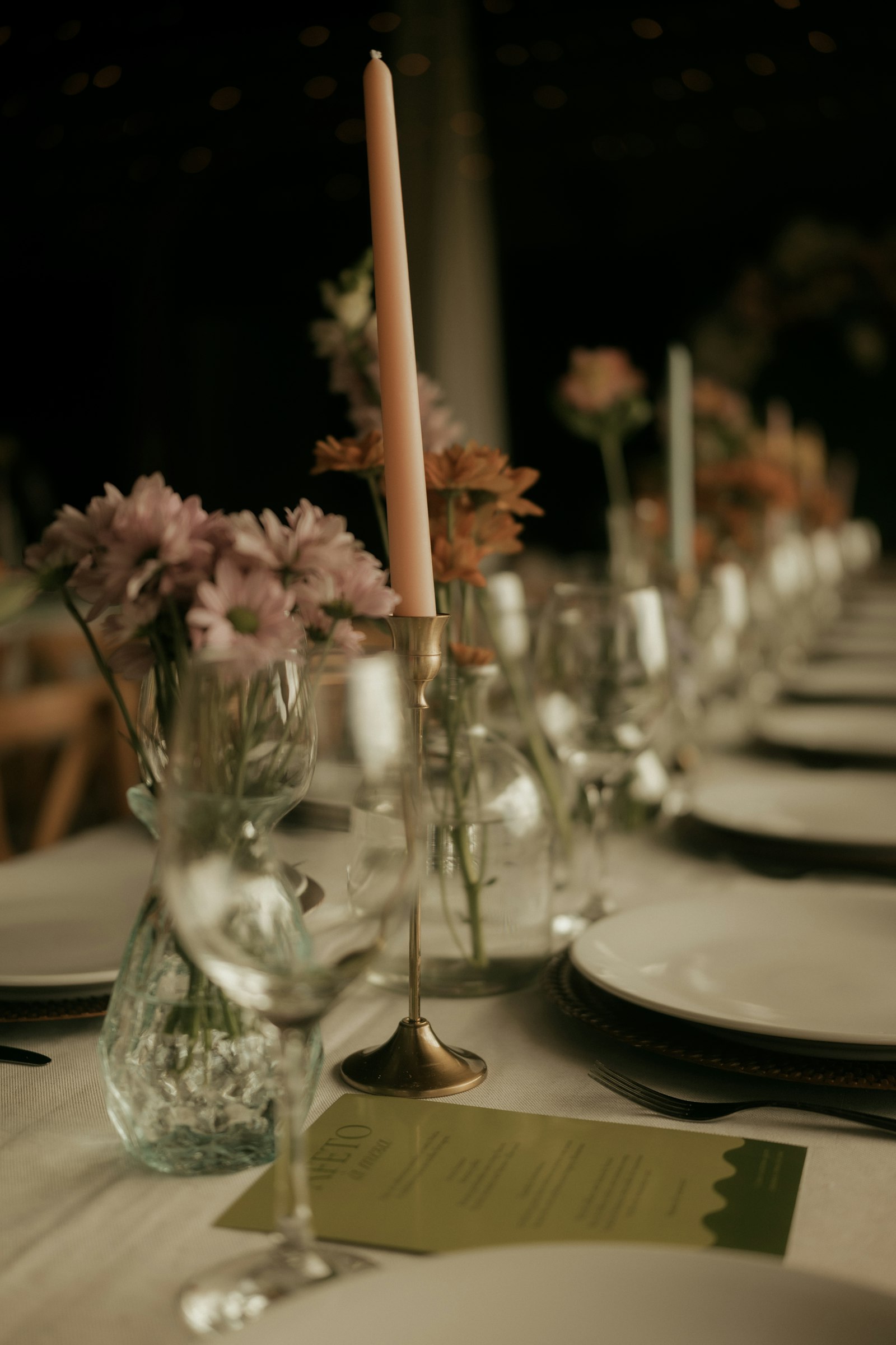 A long table at dusk with taper candles and place cards