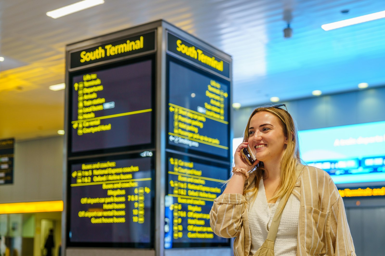 A traveller on the phone beside terminal flight screens