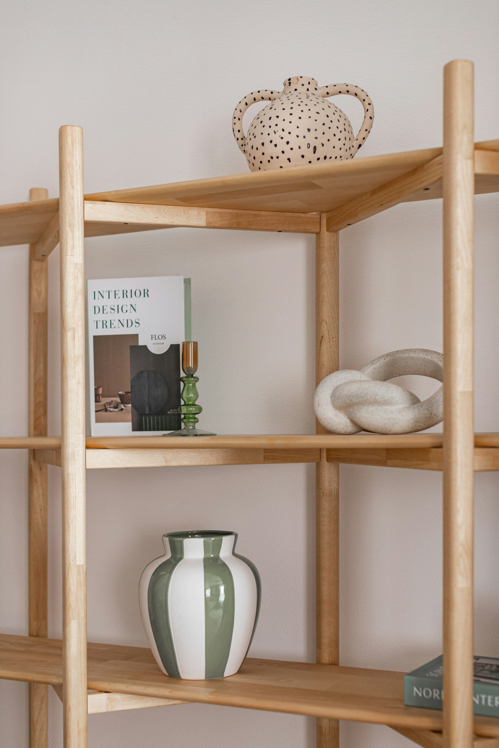 Oak shelving with a striped vase, a green glass candlestick and a ceramic knot