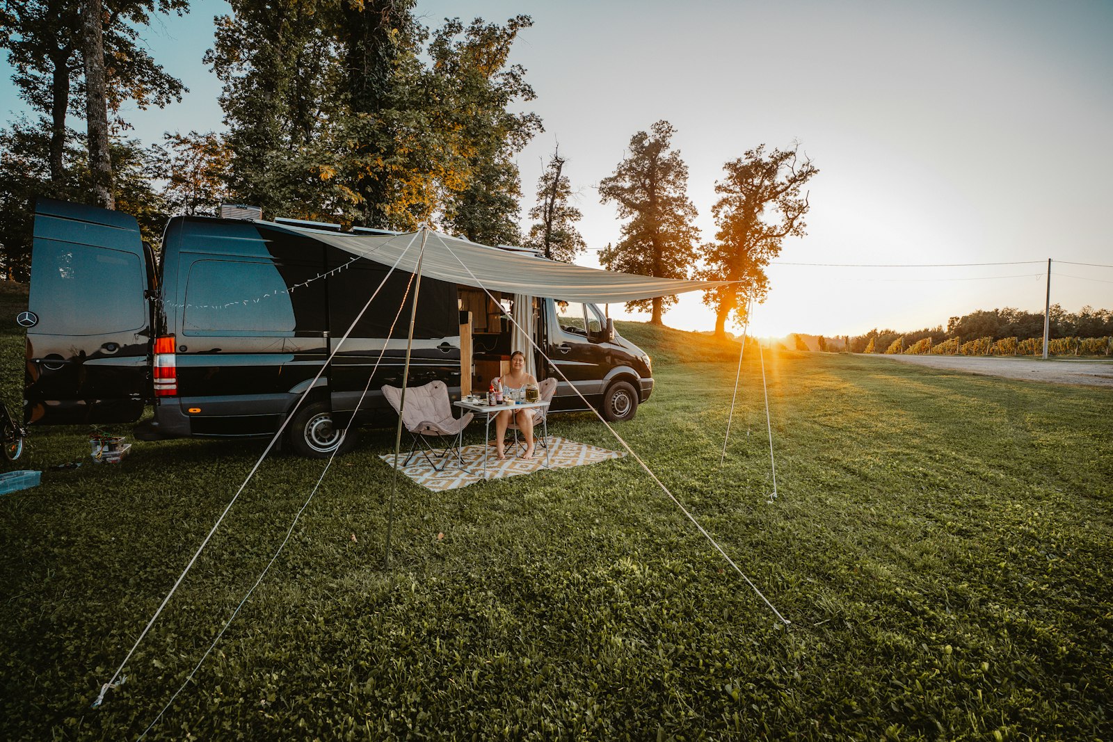 A camper with an awning on a grassy pitch at sunset