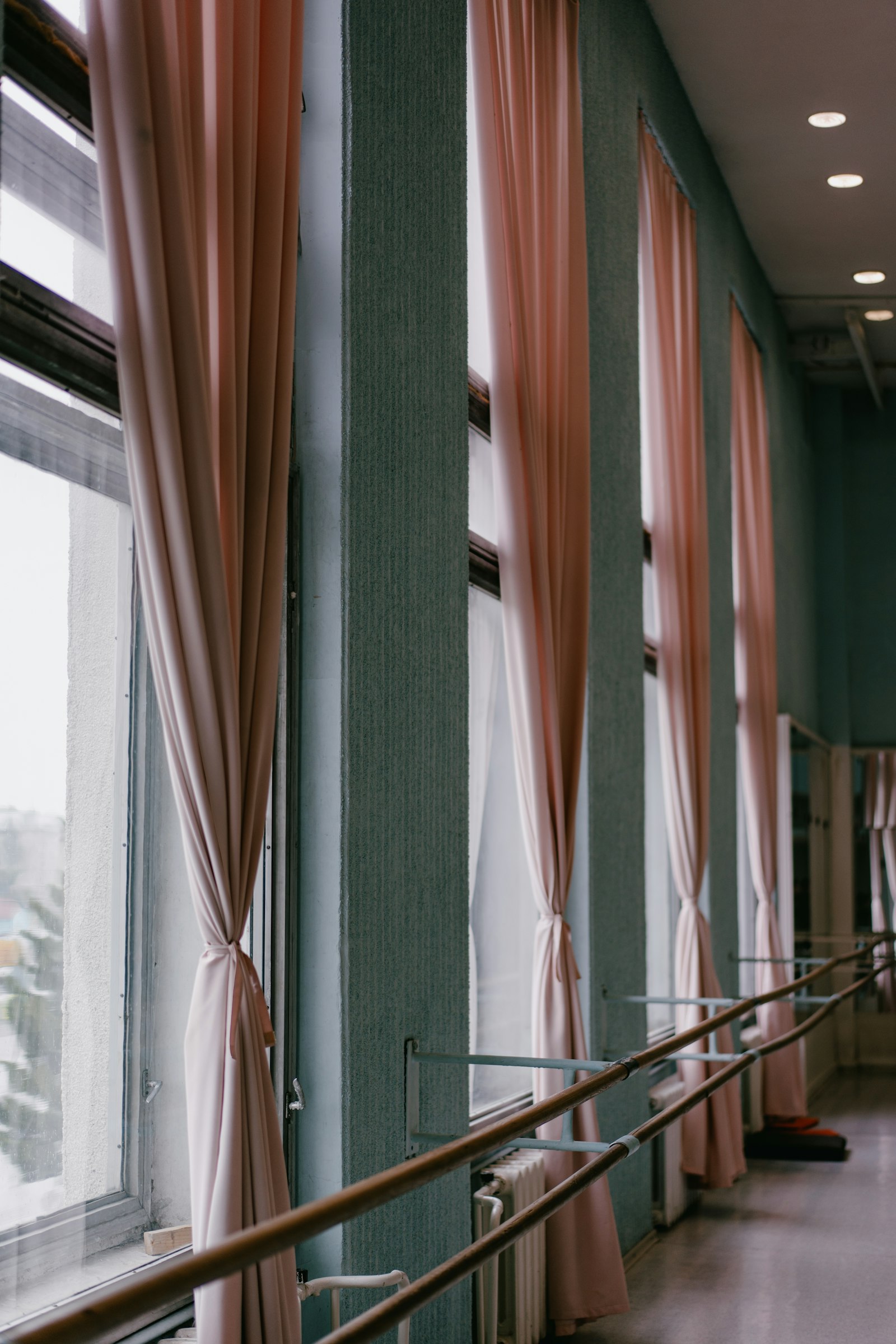 Empty ballet studio with a wooden barre running along tall windows