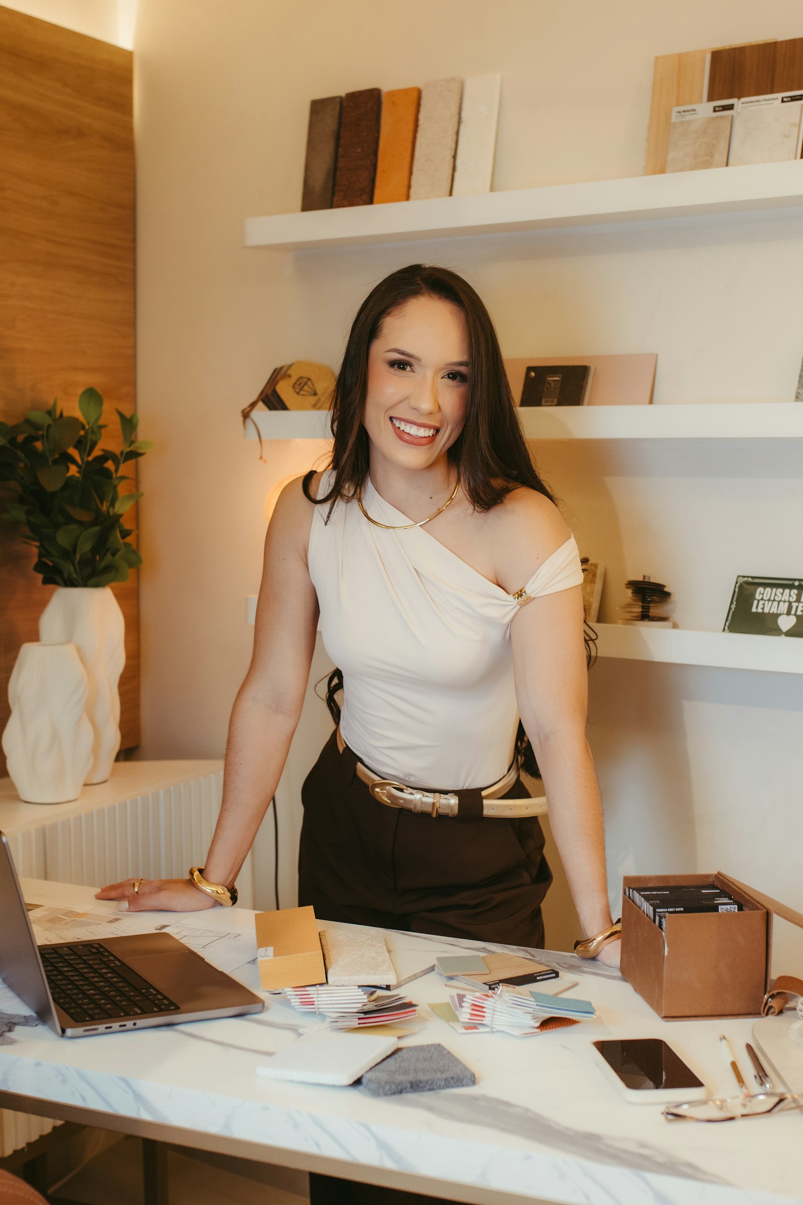 The designer at her desk with samples, drawings and a laptop