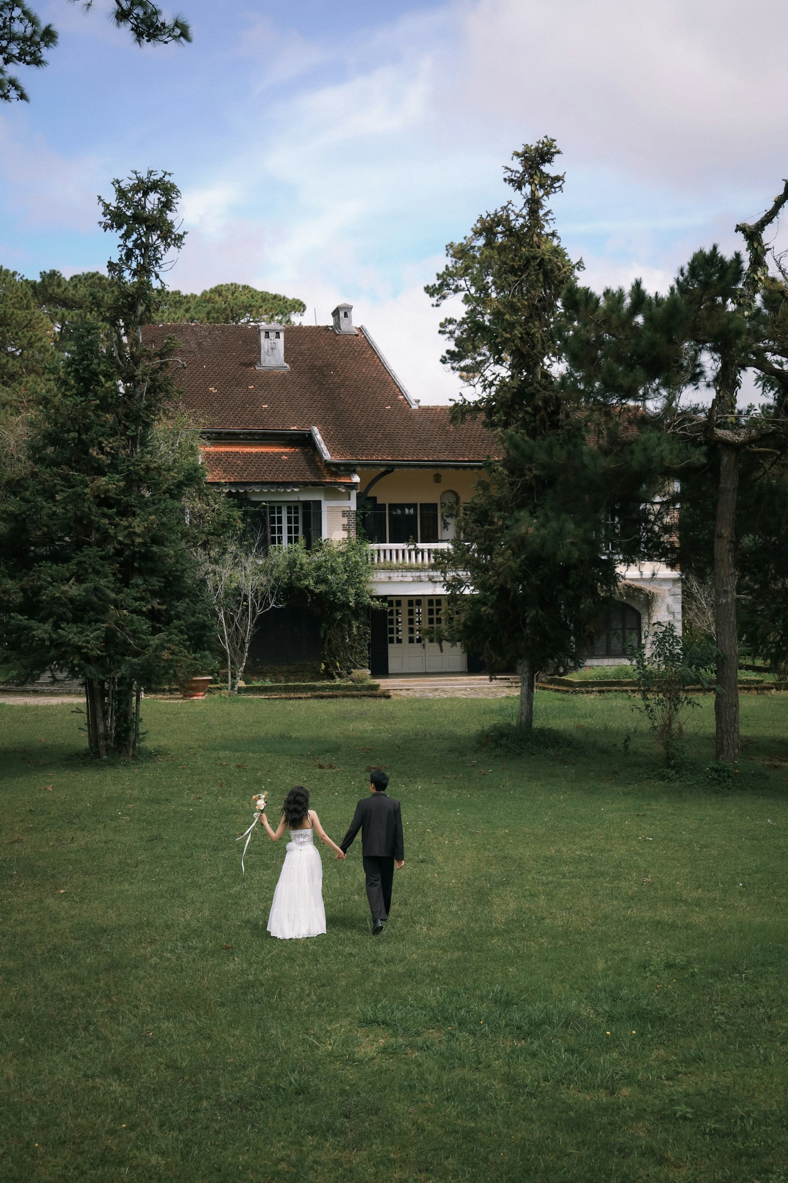 A couple walking across a lawn toward a country house