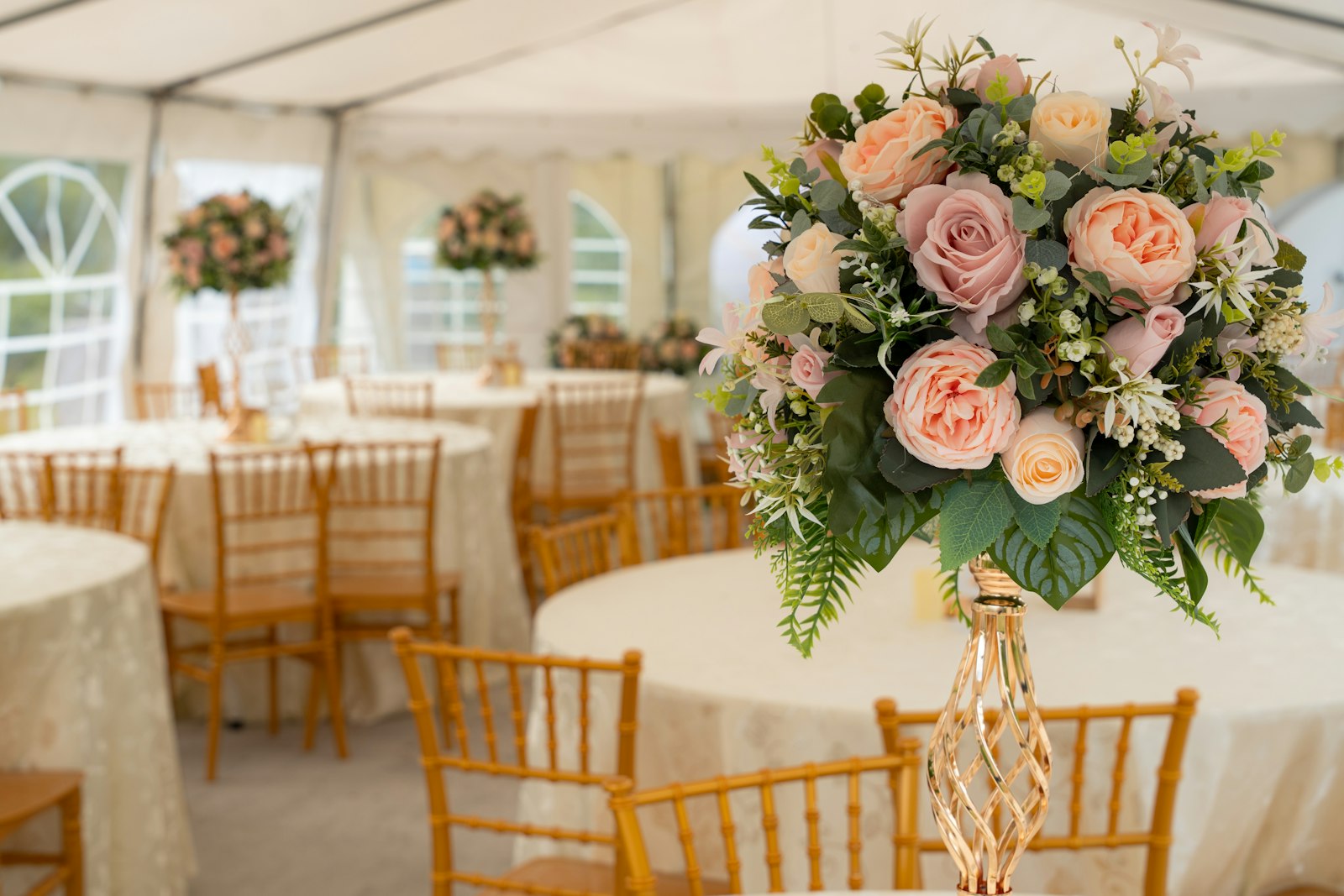 Round tables and gold chairs inside a marquee