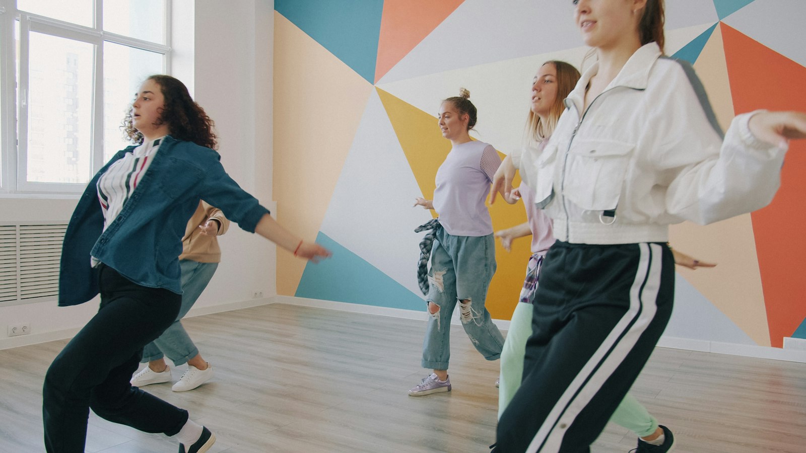 A hip hop class in front of a geometric painted wall